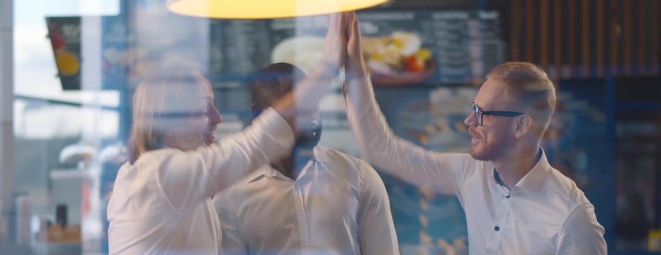 Trois personnes se félicitant après une réunion réussie dans un établissement Horeca.