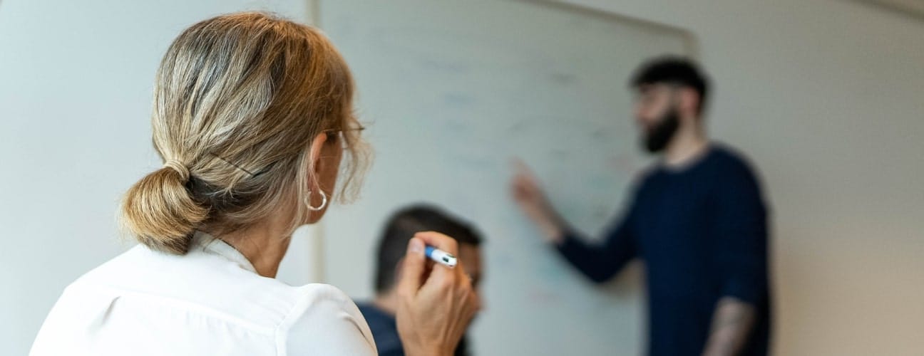 Personne lors d'une réunion stratégique pour relancer un établissement horeca, avec un tableau en arrière-plan.