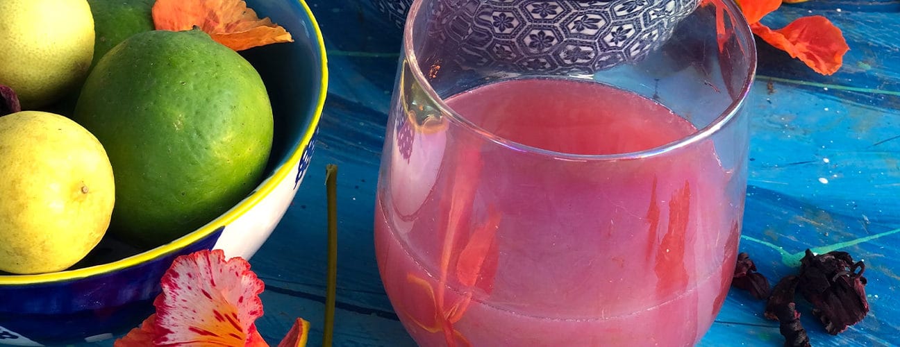 Verre de boisson rose aux fleurs et agrumes sur table bleue