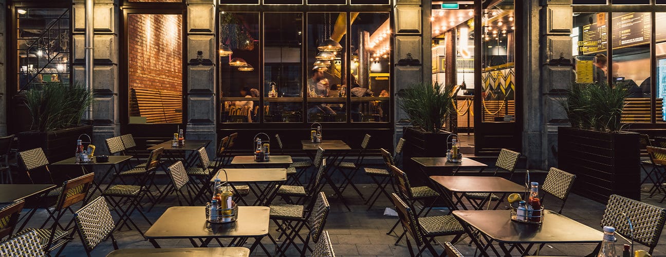 Terrasse de café éclairée la nuit avec des tables et des chaises
