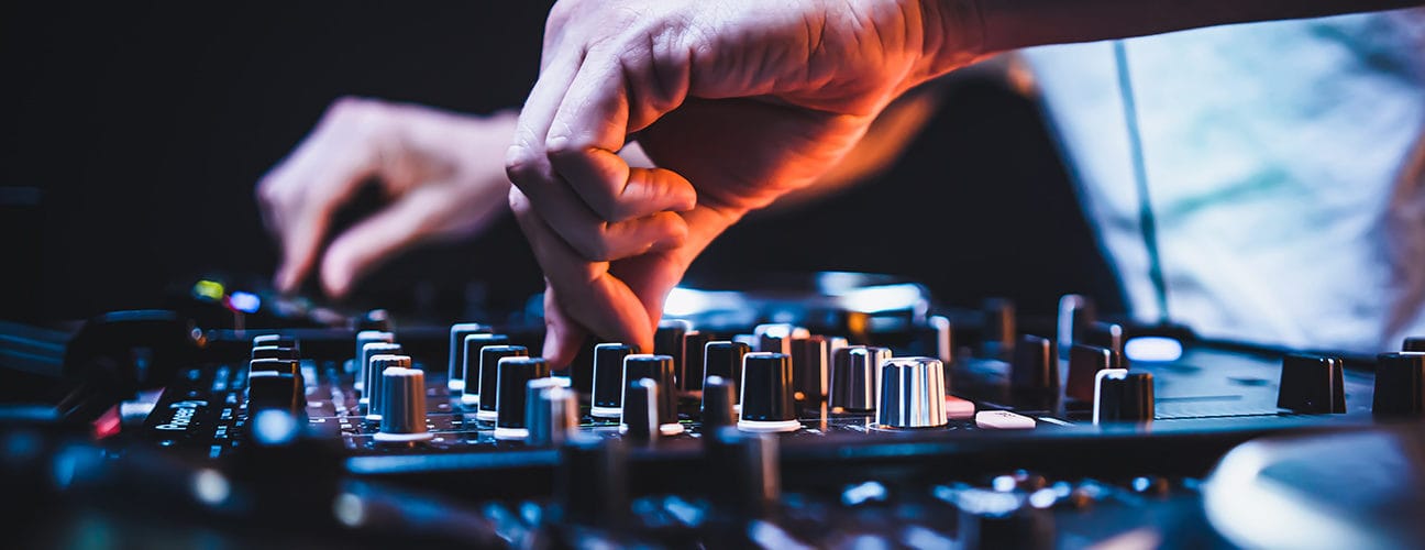 Main réglant le volume sur une table de mixage en soirée