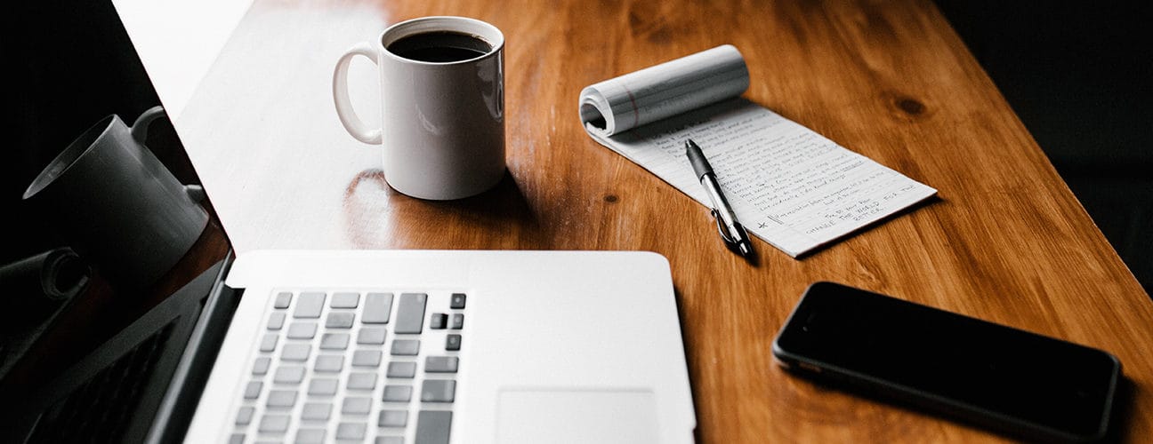 Bureau avec ordinateur portable, bloc-notes, stylo et tasse de café