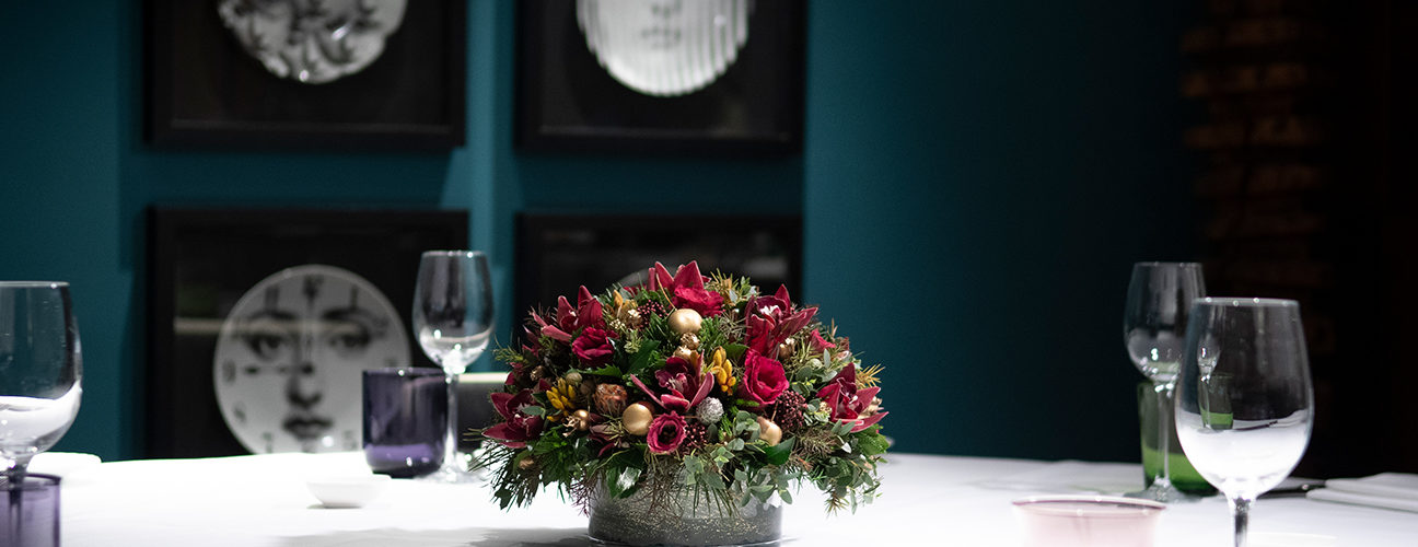 Bouquet rouge et vert sur table dressée dans un restaurant haut de gamme