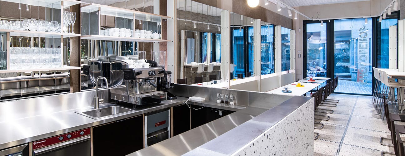 Espace de restauration moderne avec comptoir, machine à café et vue sur l'extérieur.