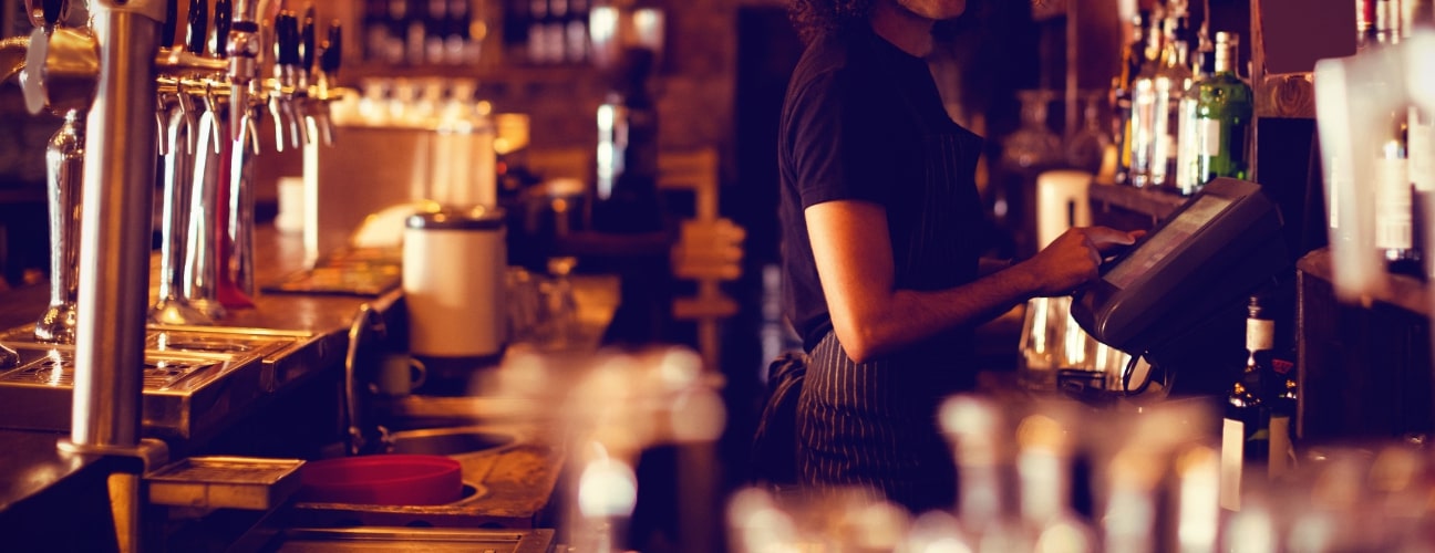 Serveur travaillant derrière un comptoir de bar dans un établissement Horeca