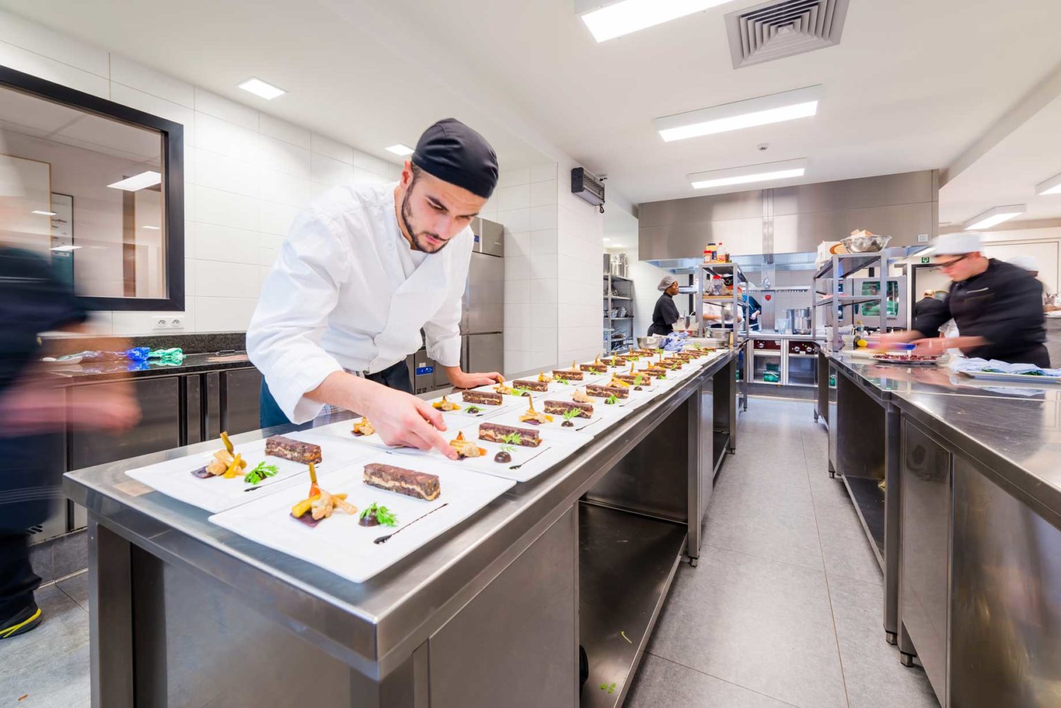 Chef en pleine préparation de plats dans une cuisine Horeca professionnelle