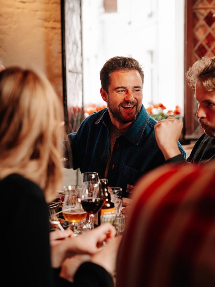Charlie Gordower attablé dans un restaurant à Bruxelles avec des clients autour d’un repas convivial Charlie Gordower attablé dans un restaurant à Bruxelles avec des clients autour d’un repas convivial